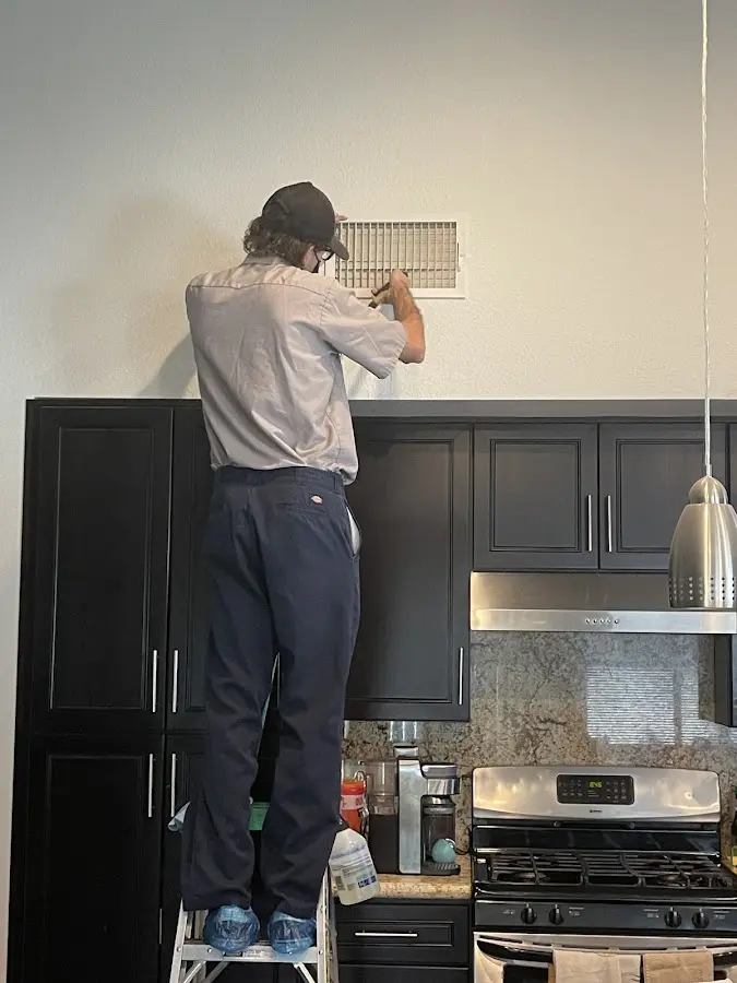 Technician inspecting an air vent during HVAC service in Fitchburg